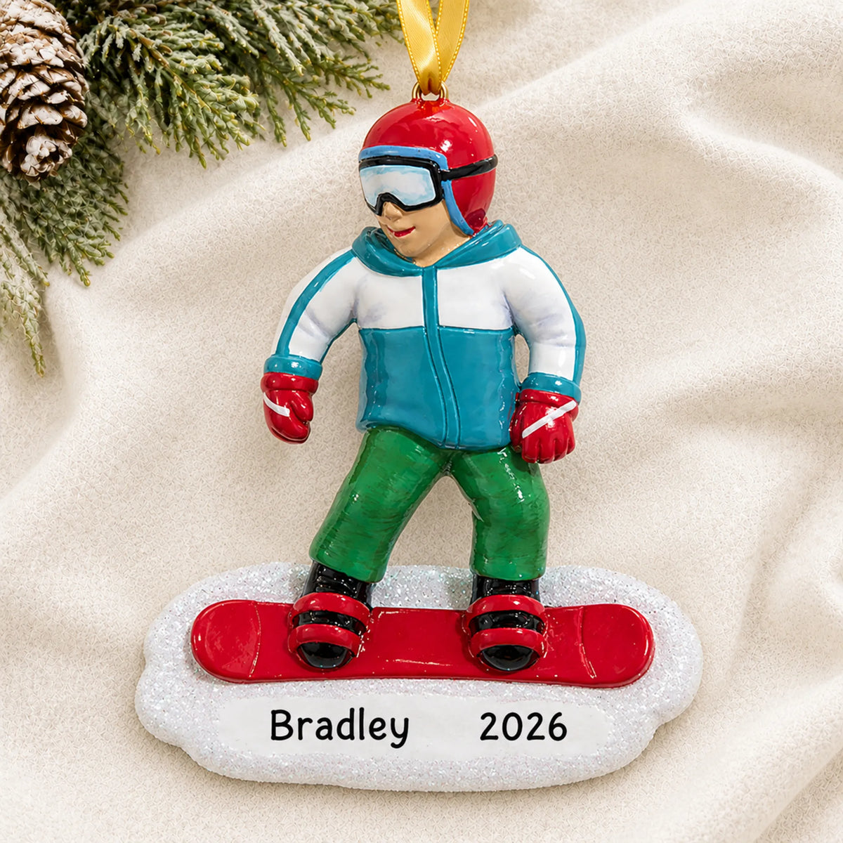 Personalized snowboarding guy christmas ornament laid on a soft white knit blanket