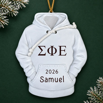 Personalized fraternity hoodie Christmas ornament with name and year, shown on a green holiday background