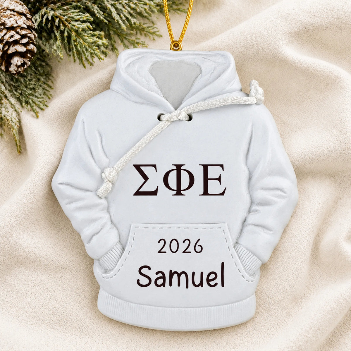 Personalized fraternity hoodie Christmas ornament shown on a soft white blanket
