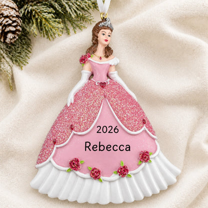 Personalized princess pink dress christmas ornament laid on a soft white knit blanket