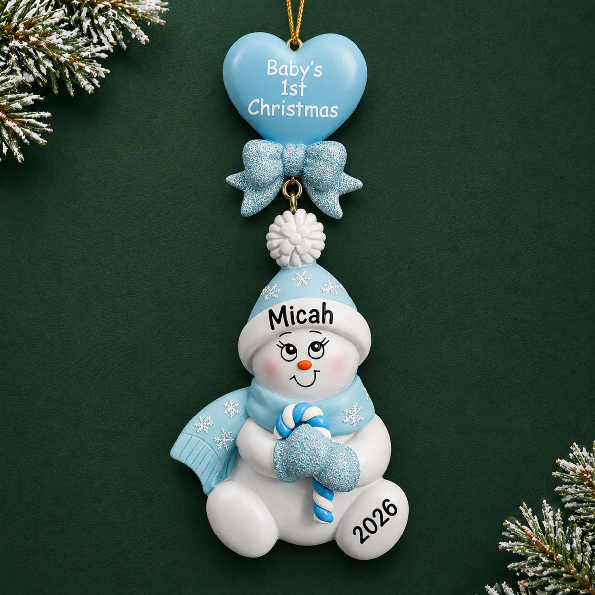 Personalized blue baby's 1st christmas candy cane snowbaby ornament on a dark green pine background