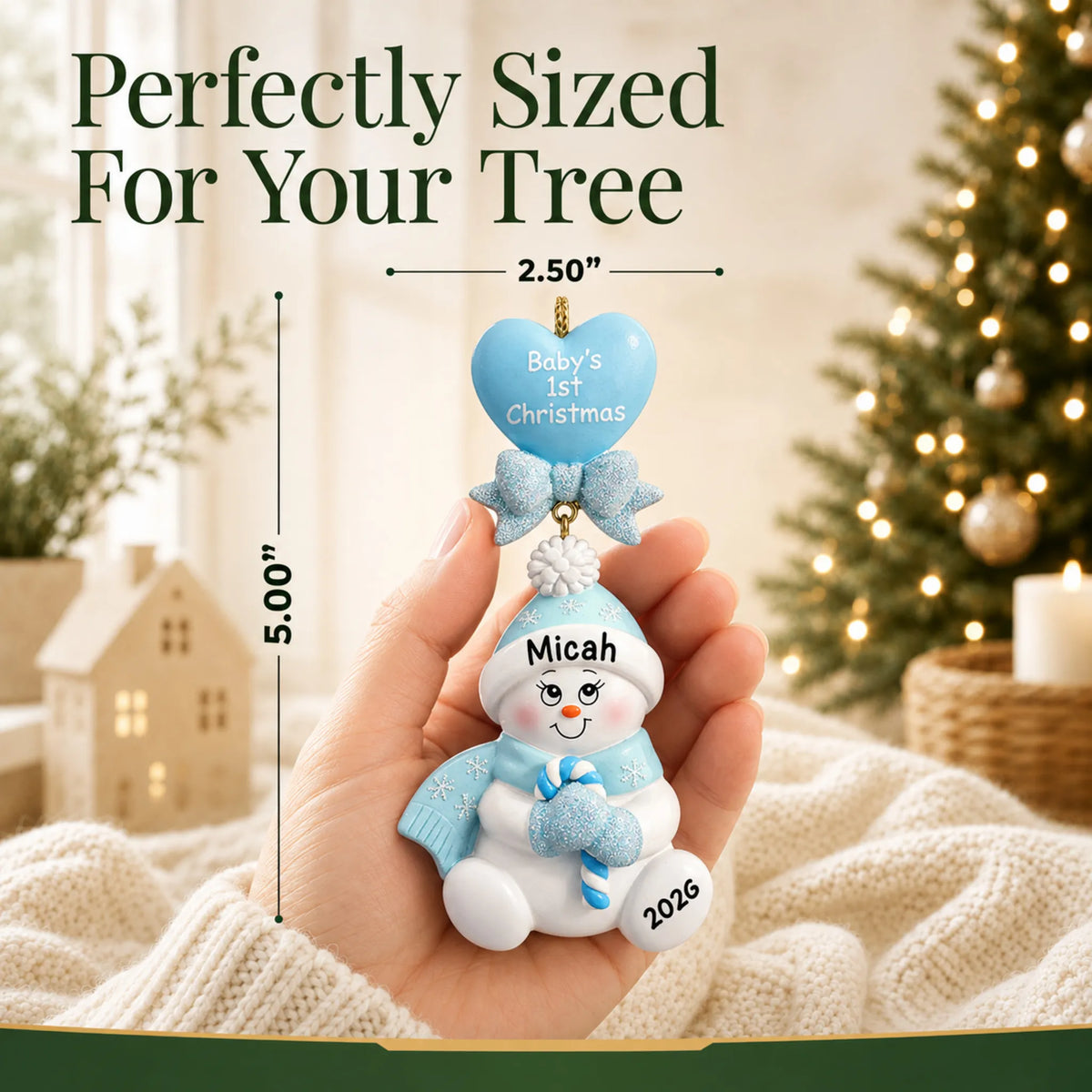 Size guide: the personalized blue baby's 1st christmas candy cane snowbaby ornament shown in hand next to a Christmas tree