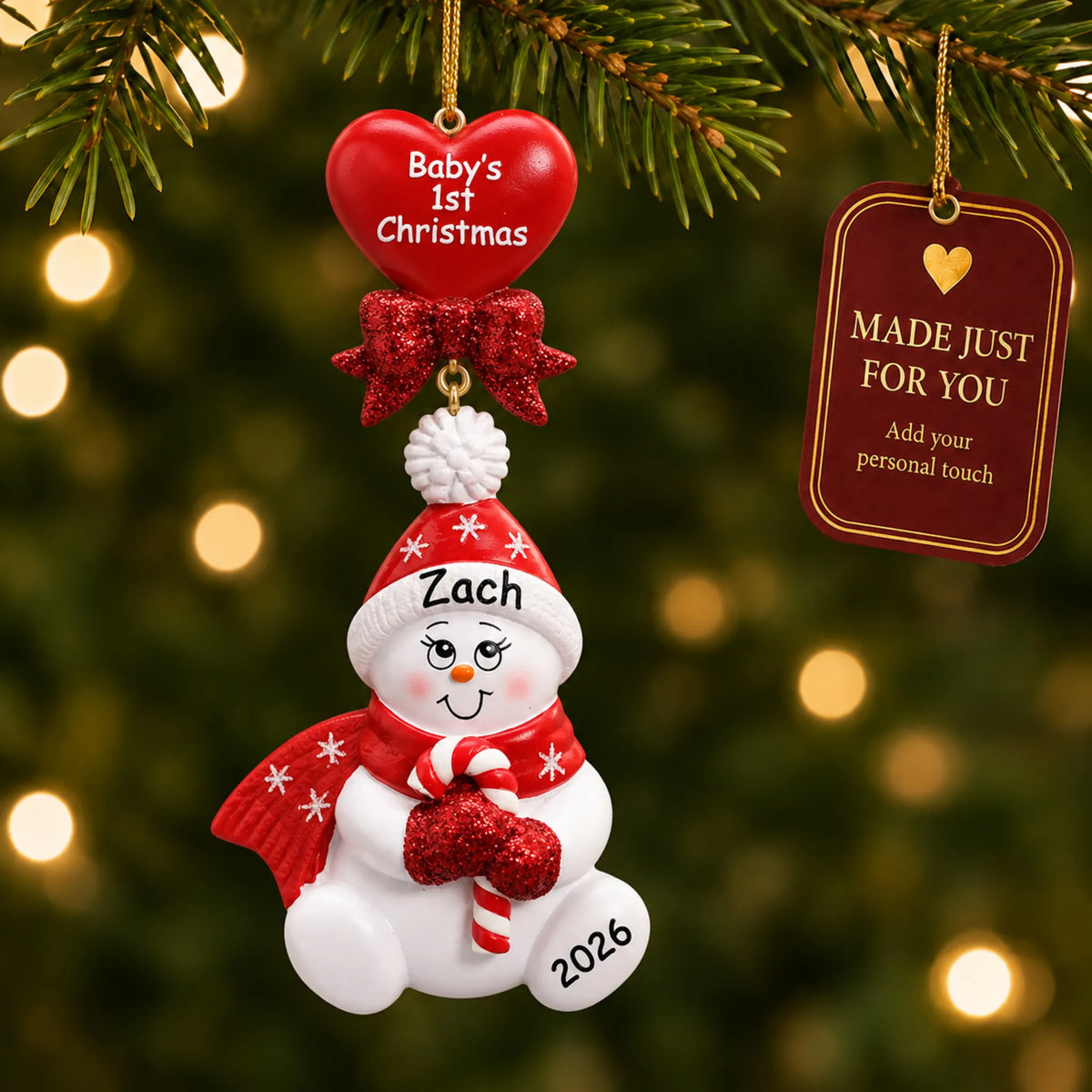 Red baby's 1st christmas candy cane snowbaby ornament hanging on a lit Christmas tree with a Made Just For You gift tag