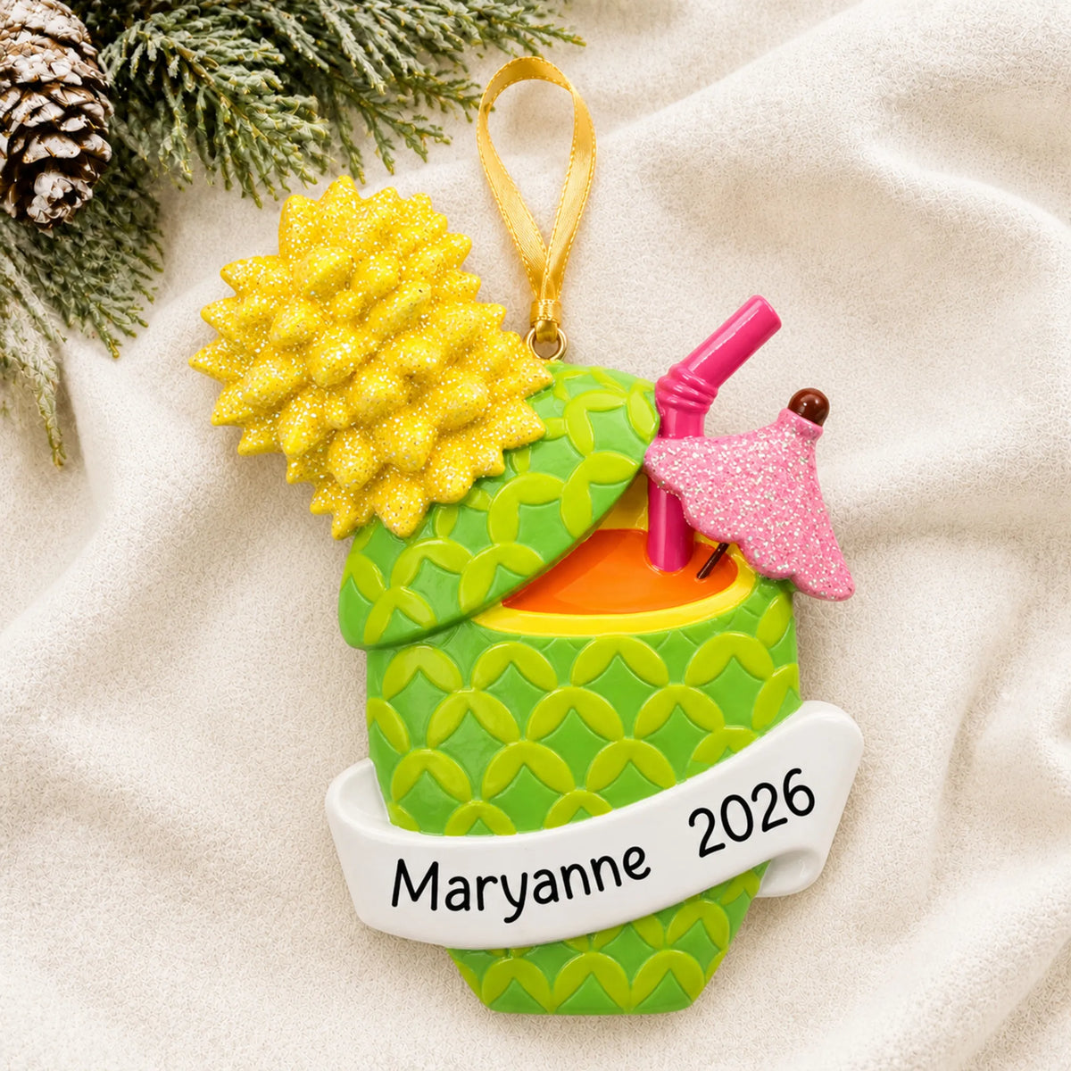 Personalized Pineapple Cocktail christmas ornament laid on a soft white knit blanket