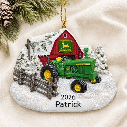 Personalized green farm tractor christmas ornament laid on a soft white knit blanket