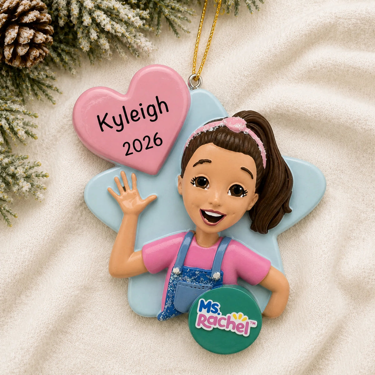 Personalized Ms. Rachel christmas ornament laid on a soft white knit blanket