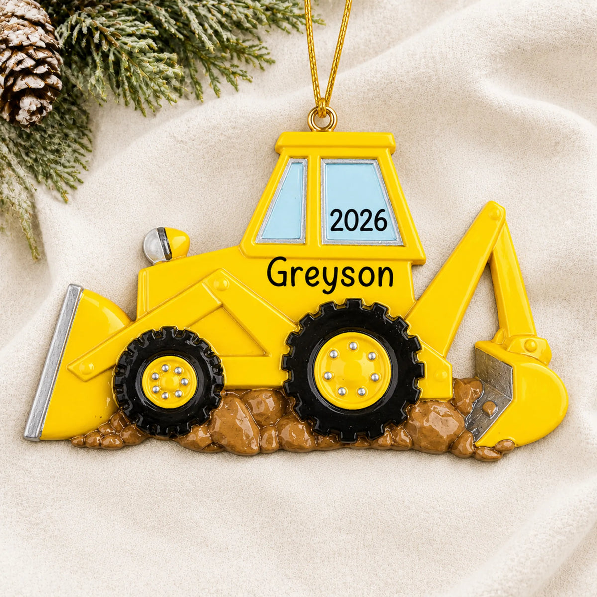 Personalized backhoe christmas ornament laid on a soft white knit blanket