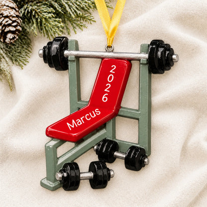 Personalized weight lifting bench christmas ornament laid on a soft white knit blanket