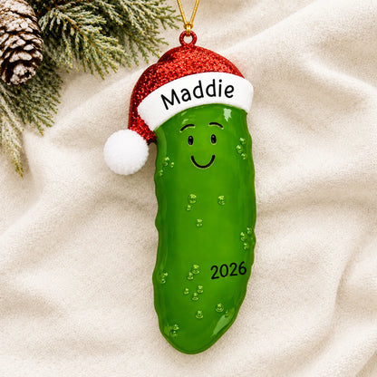Personalized Christmas Pickle ornament laid on a soft white knit blanket