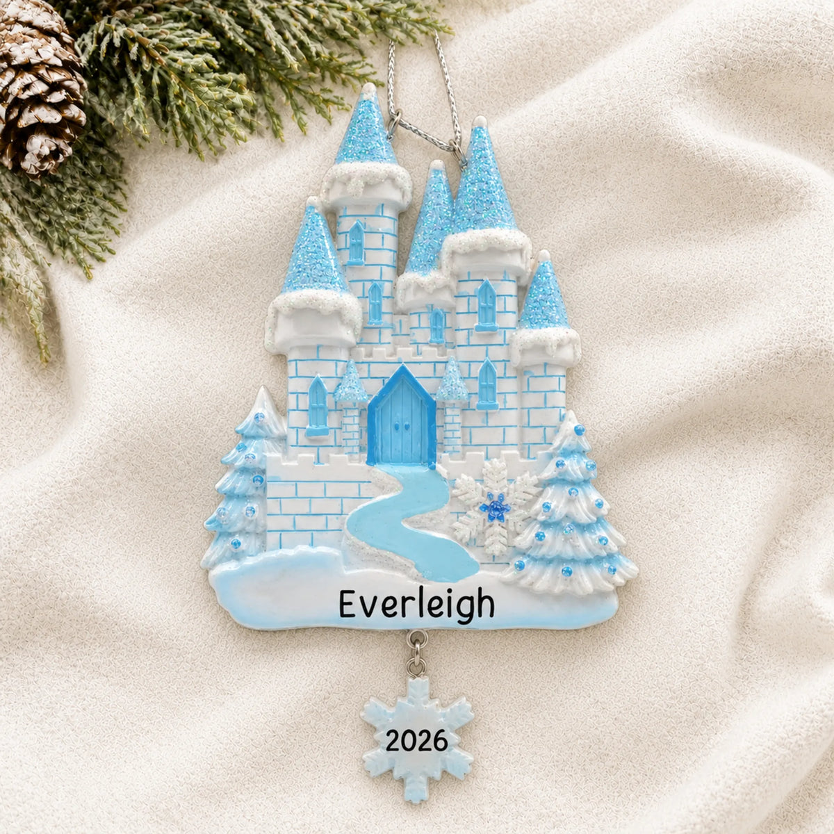 Personalized ice castle christmas ornament laid on a soft white knit blanket