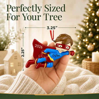 Size guide: the personalized super hero christmas ornament is 3.25 in wide by 2.25 in tall, shown in hand