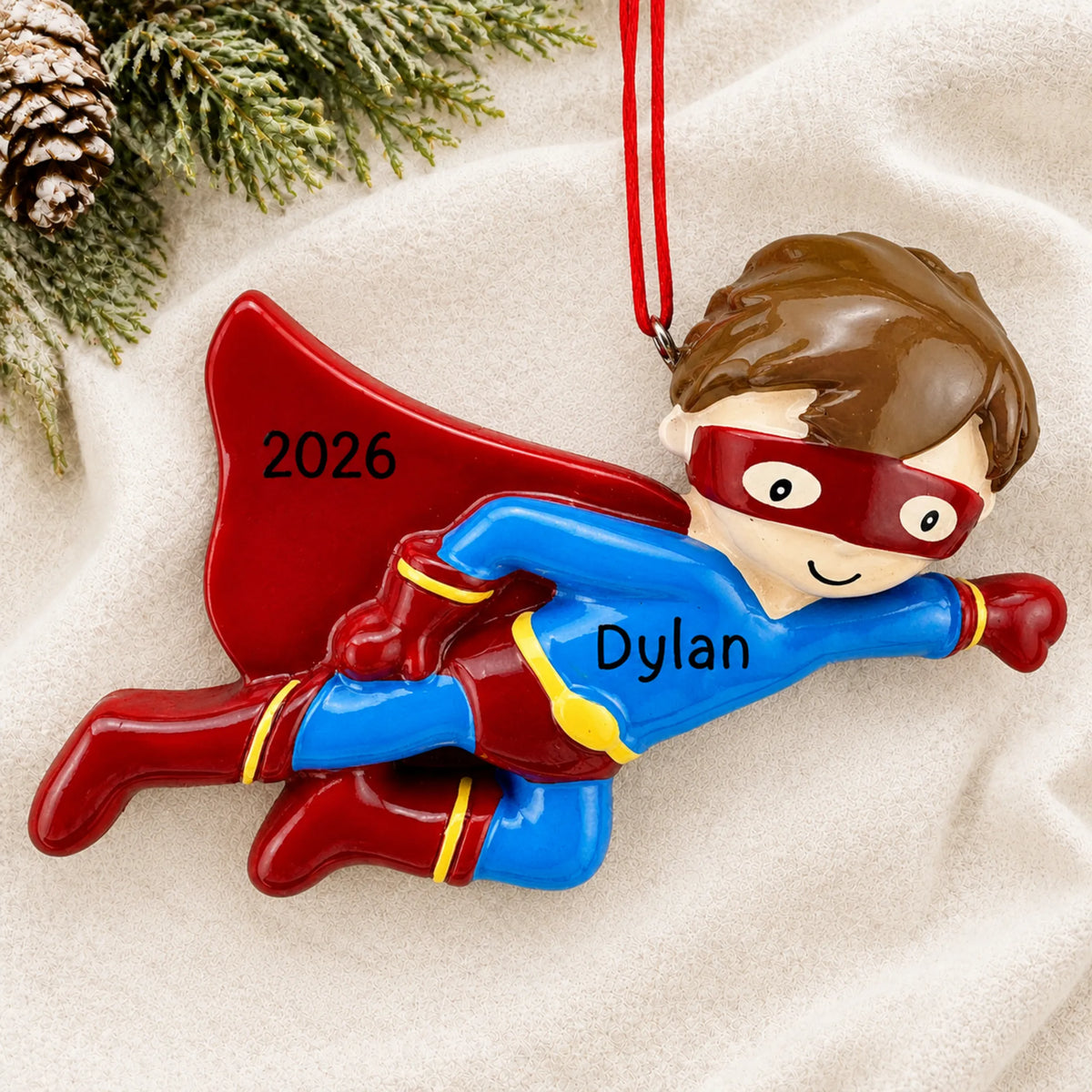 Personalized super hero christmas ornament laid on a soft white knit blanket