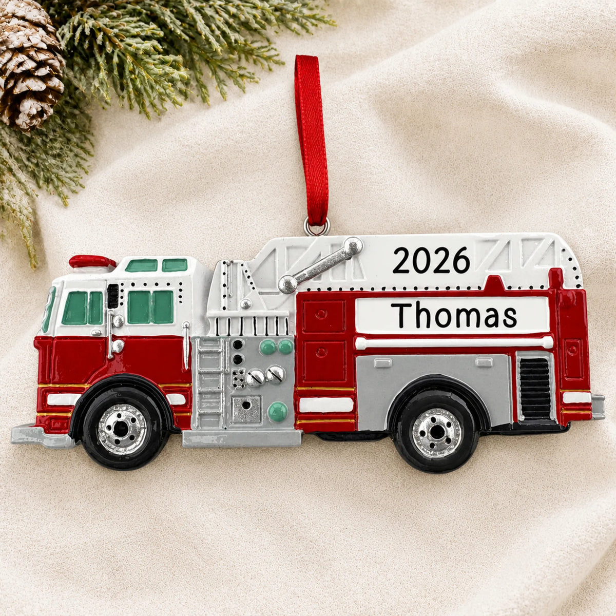 Personalized firetruck christmas ornament laid on a soft white knit blanket