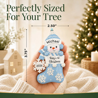 Size guide: the personalized blue snowman baby's 1st christmas ornament is 2.50 in wide by 3.75 in tall, shown in hand