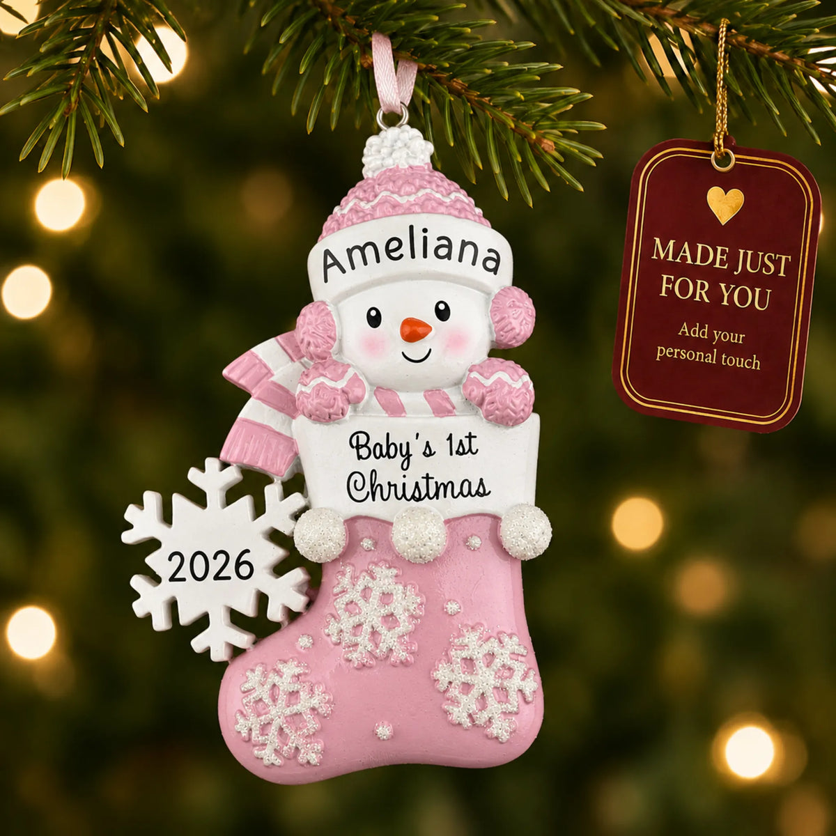 Pink snowman baby's 1st christmas ornament hanging on a lit Christmas tree with a Made Just For You gift tag