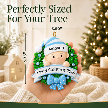 Size guide: the personalized blue baby boy wreath christmas ornament is 3.50 in wide by 3.75 in tall, shown in hand