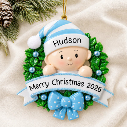Personalized blue baby boy wreath christmas ornament laid on a soft white knit blanket