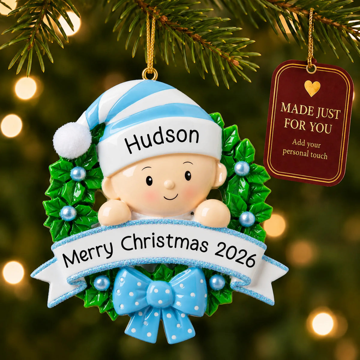 Blue baby boy wreath christmas ornament hanging on a lit Christmas tree with a Made Just For You gift tag