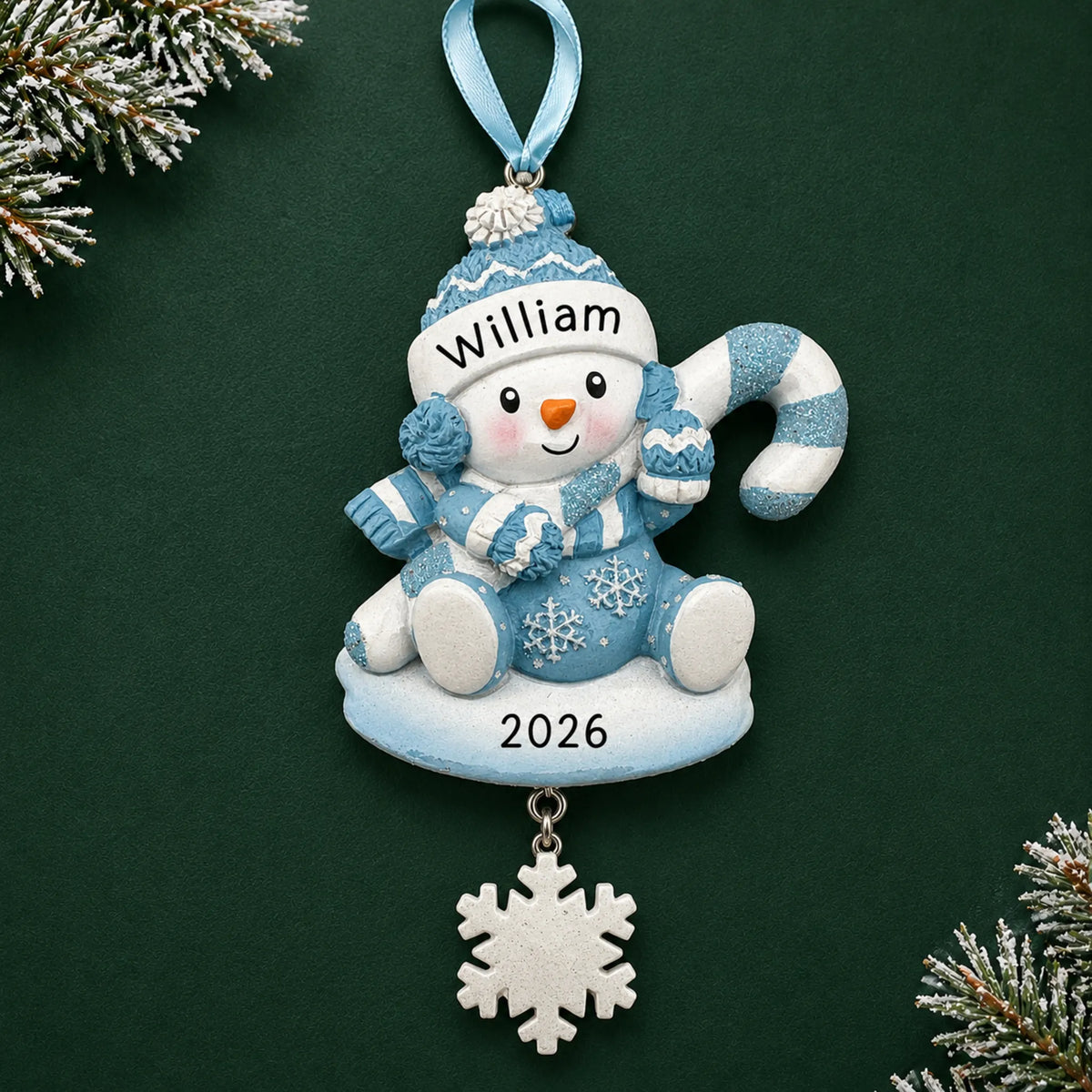 Personalized baby boy snowman christmas ornament on a dark green pine background