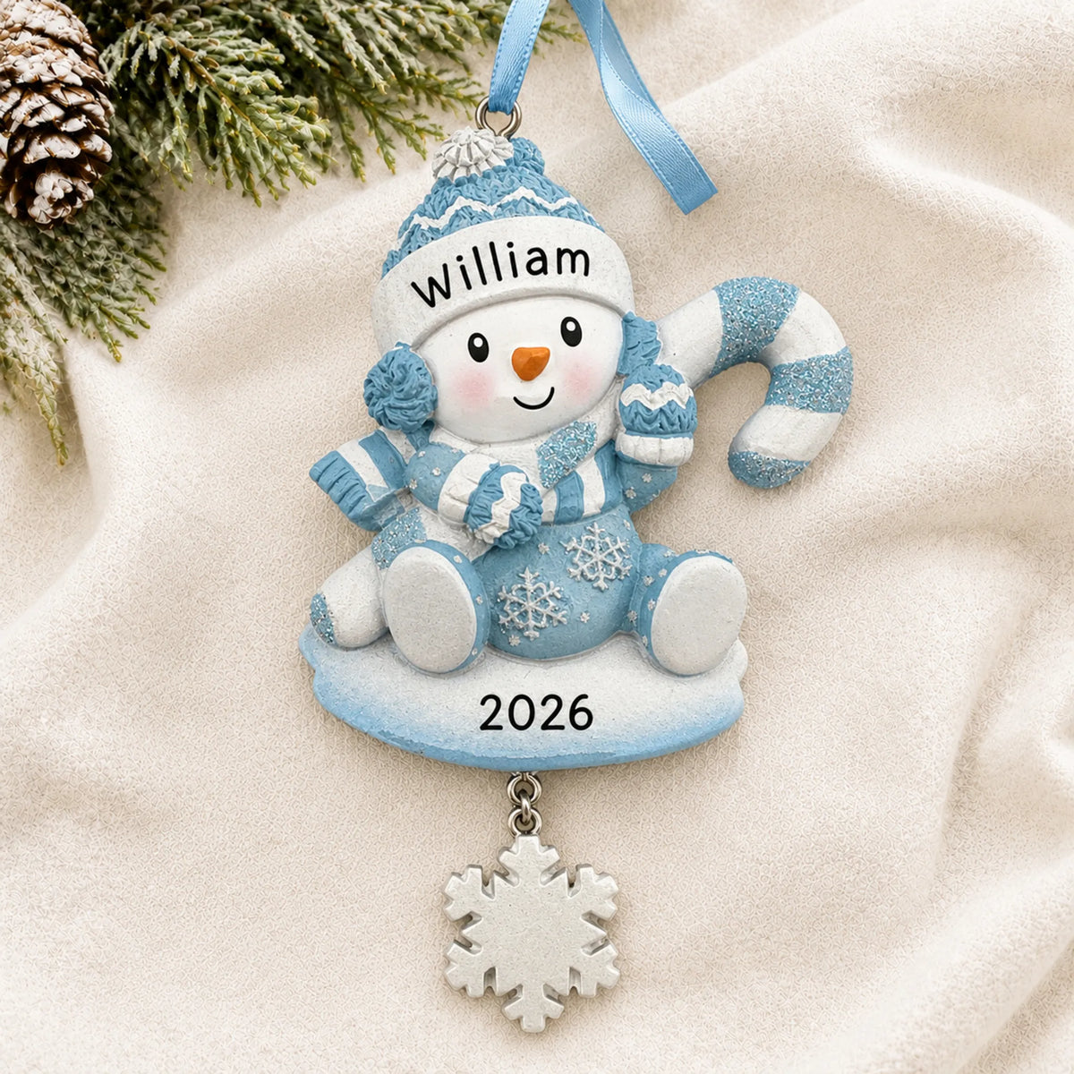 Personalized baby boy snowman christmas ornament laid on a soft white knit blanket
