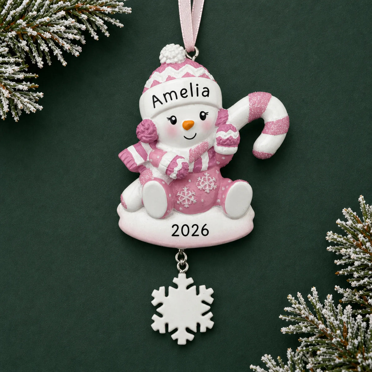 Personalized baby girl snowman christmas ornament on a dark green pine background