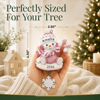 Size guide: the personalized baby girl snowman christmas ornament shown in hand next to a Christmas tree
