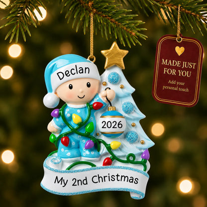 Blue baby's 2nd christmas ornament hanging on a lit Christmas tree with a Made Just For You gift tag