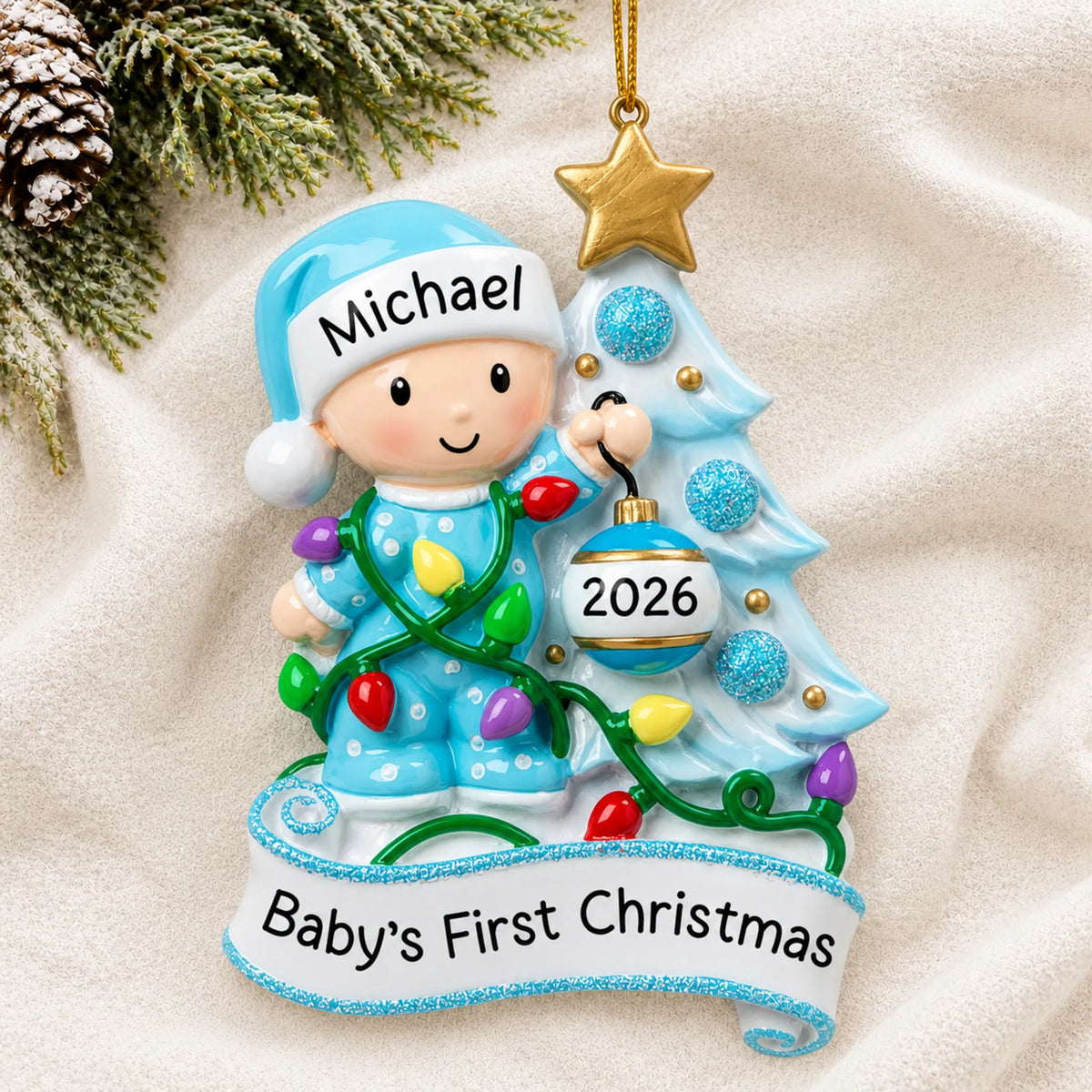 Personalized blue baby's 1st christmas tree ornament laid on a soft white knit blanket