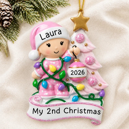 Personalized pink baby's 2nd christmas ornament laid on a soft white knit blanket