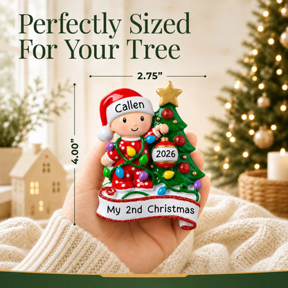 Size guide: the personalized red baby's 2nd christmas ornament is 2.75 in wide by 4.00 in tall, shown in hand