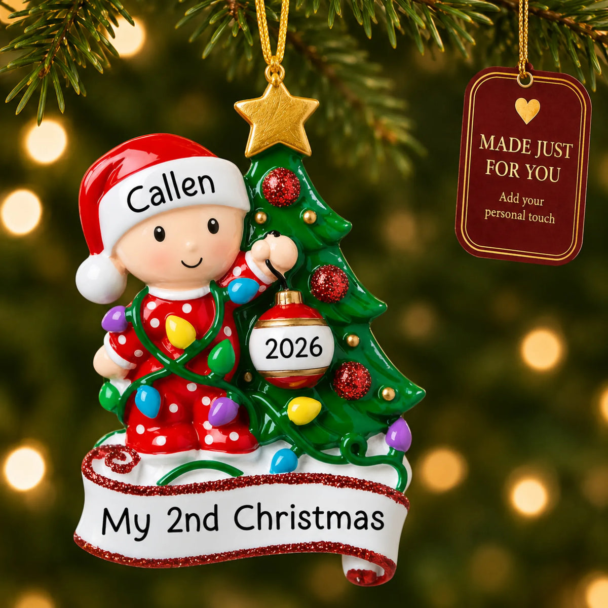 Red baby's 2nd christmas ornament hanging on a lit Christmas tree with a Made Just For You gift tag