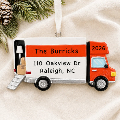 Personalized Moving Truck christmas ornament laid on a soft white knit blanket