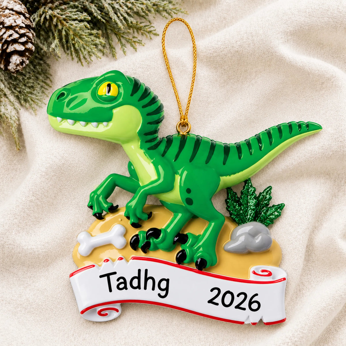 Personalized green t-rex christmas ornament laid on a soft white knit blanket