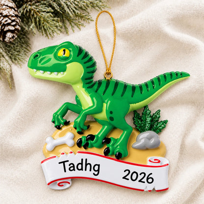 Personalized green t-rex christmas ornament laid on a soft white knit blanket