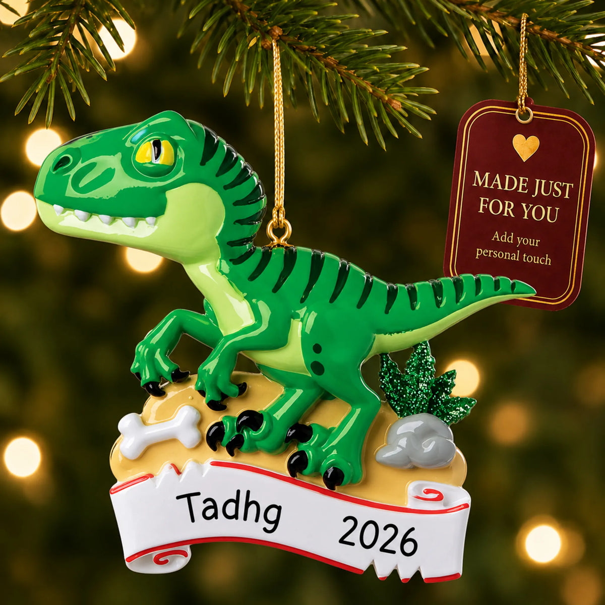 Green t-rex christmas ornament hanging on a lit Christmas tree with a Made Just For You gift tag