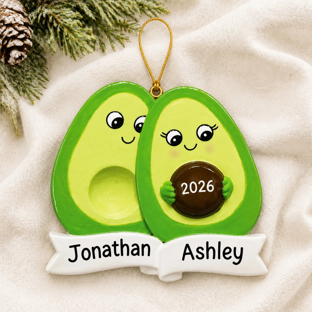 Personalized Avocado Expecting Couple christmas ornament laid on a soft white knit blanket