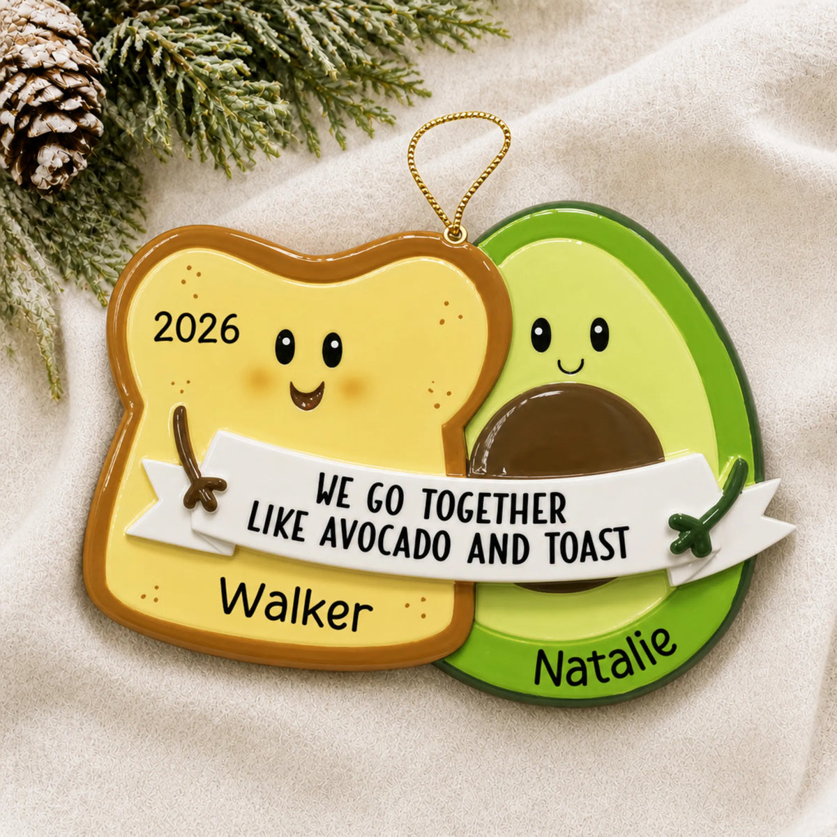 Personalized Avocado & Toast christmas ornament laid on a soft white knit blanket