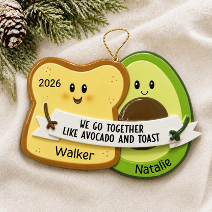 Personalized Avocado & Toast christmas ornament laid on a soft white knit blanket