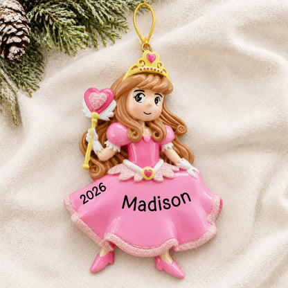 Personalized pink princess christmas ornament laid on a soft white knit blanket