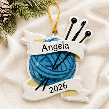 Personalized knitting yarn and needles christmas ornament laid on a soft white knit blanket