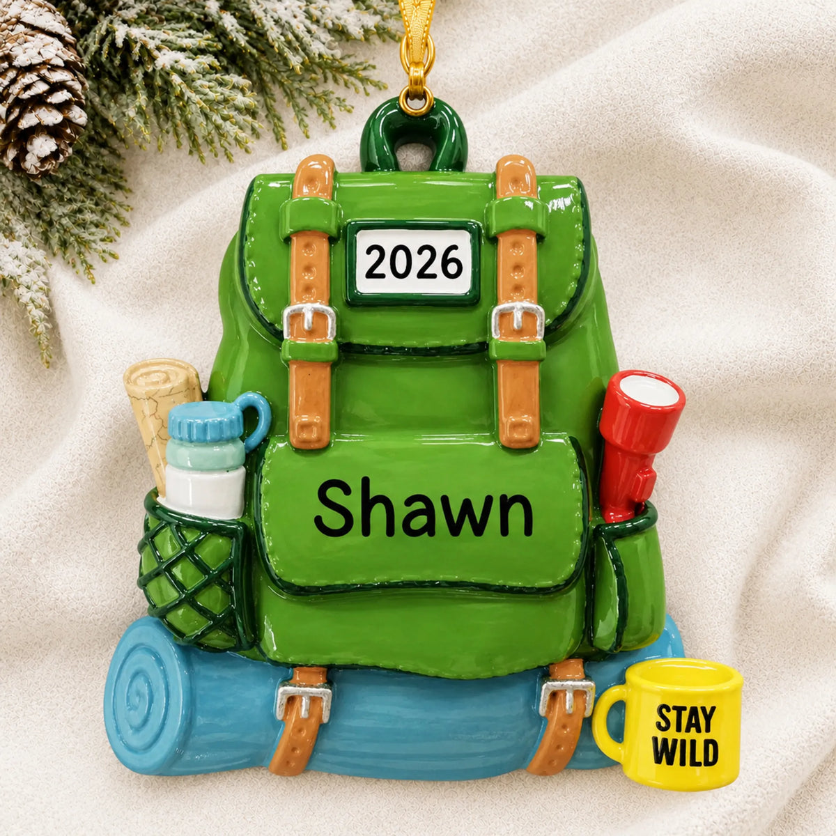 Personalized hiking backpack christmas ornament laid on a soft white knit blanket