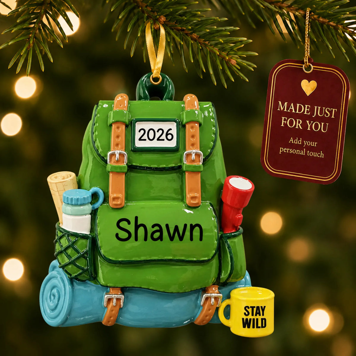 Hiking backpack christmas ornament hanging on a lit Christmas tree with a Made Just For You gift tag