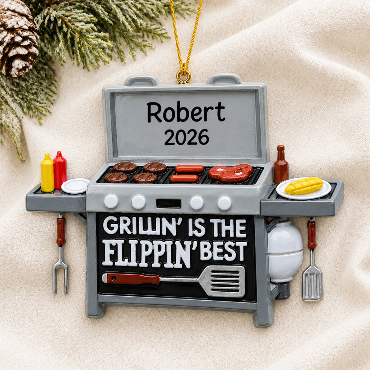 Personalized BBQ Grilling christmas ornament laid on a soft white knit blanket