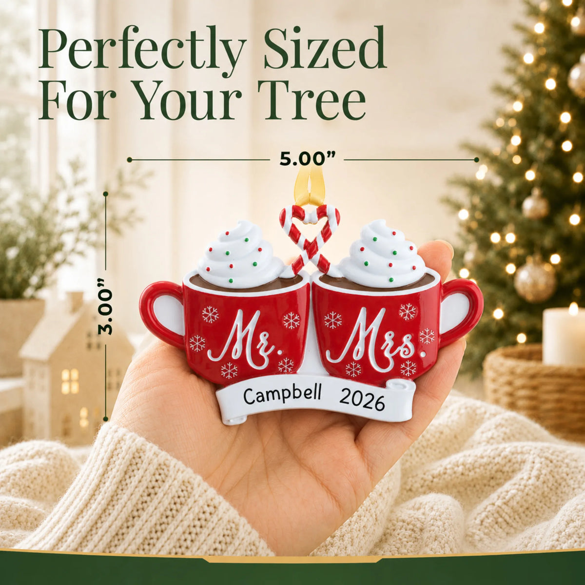 Size guide: the personalized Mr & Mrs Hot Cocoa christmas ornament is 5.00 in wide by 3.00 in tall, shown in hand