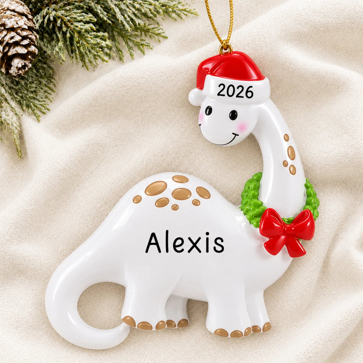 Personalized white dinosaur christmas ornament laid on a soft white knit blanket