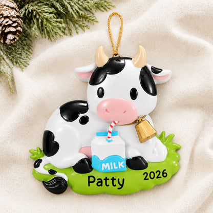 Personalized dairy cow christmas ornament laid on a soft white knit blanket