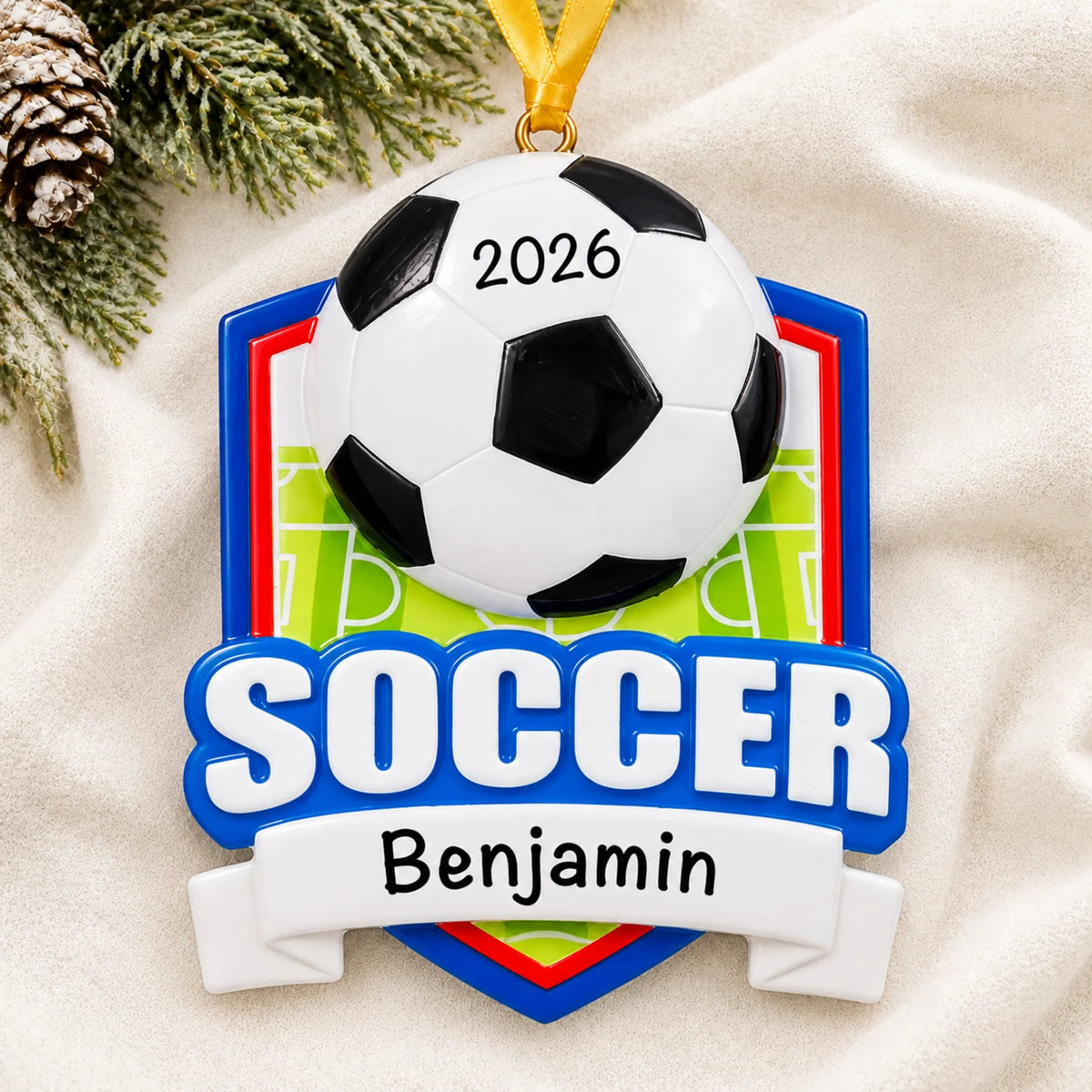 Personalized soccer shield christmas ornament laid on a soft white knit blanket