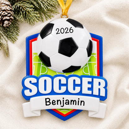 Personalized soccer shield christmas ornament laid on a soft white knit blanket