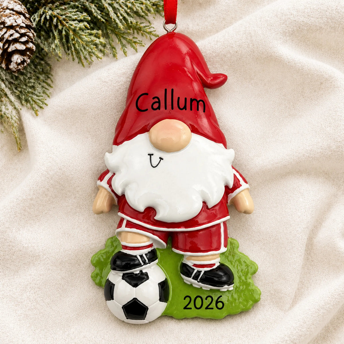 Personalized soccer gnome christmas ornament laid on a soft white knit blanket