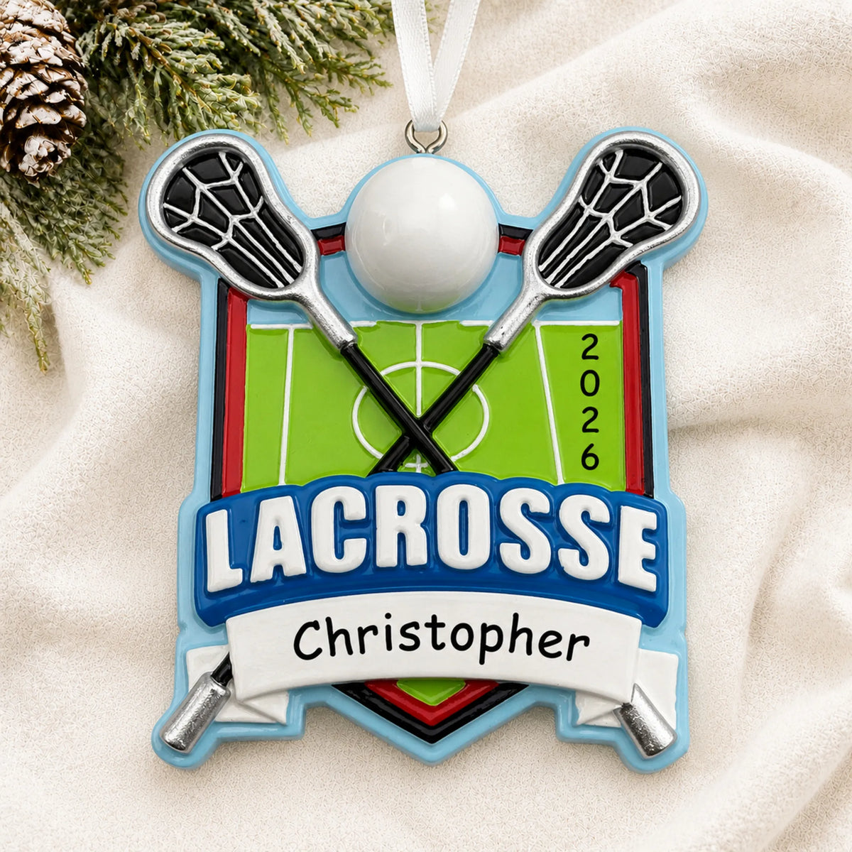 Personalized lacrosse christmas ornament laid on a soft white knit blanket